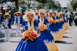 Dancers in vibrant blue dresses with gold accents performing in a street festival parade.