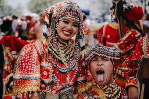 Festival participants wearing ornate red and gold traditional costumes during a cultural celebration.