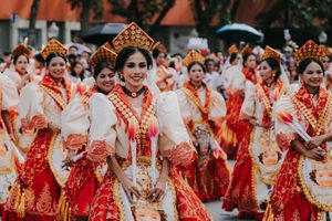 Dancers in vibrant red and white traditional Filipino costumes perform during a cultural festival celebration.