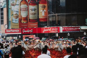 Festival performers dance beneath large advertising billboards during a street celebration.