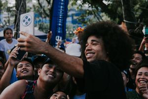 Excited festival crowd gathers for selfies during an outdoor event.