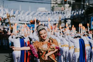 Festival performer in ornate gold costume dances energetically during street celebration.
