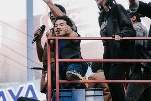Energetic performers singing on elevated platform at outdoor festival.