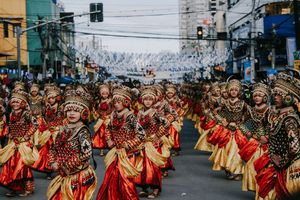 Traditional dancers in red and gold costumes perform synchronized routine during street festival.