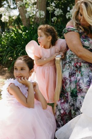 A series of candid moments showing people in pink and floral dresses sharing tender interactions outdoors.