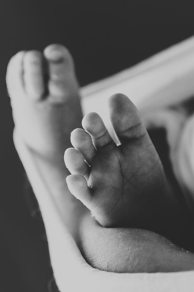 Close-up black and white detail shots of tiny newborn baby fingers and toes.