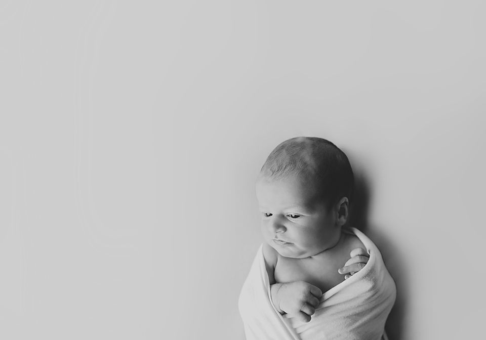 Minimalist black and white portraits of a newborn baby in various poses.