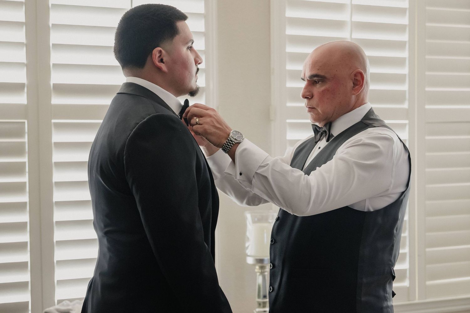 A groom gets help with his tie and final adjustments before a wedding ceremony.