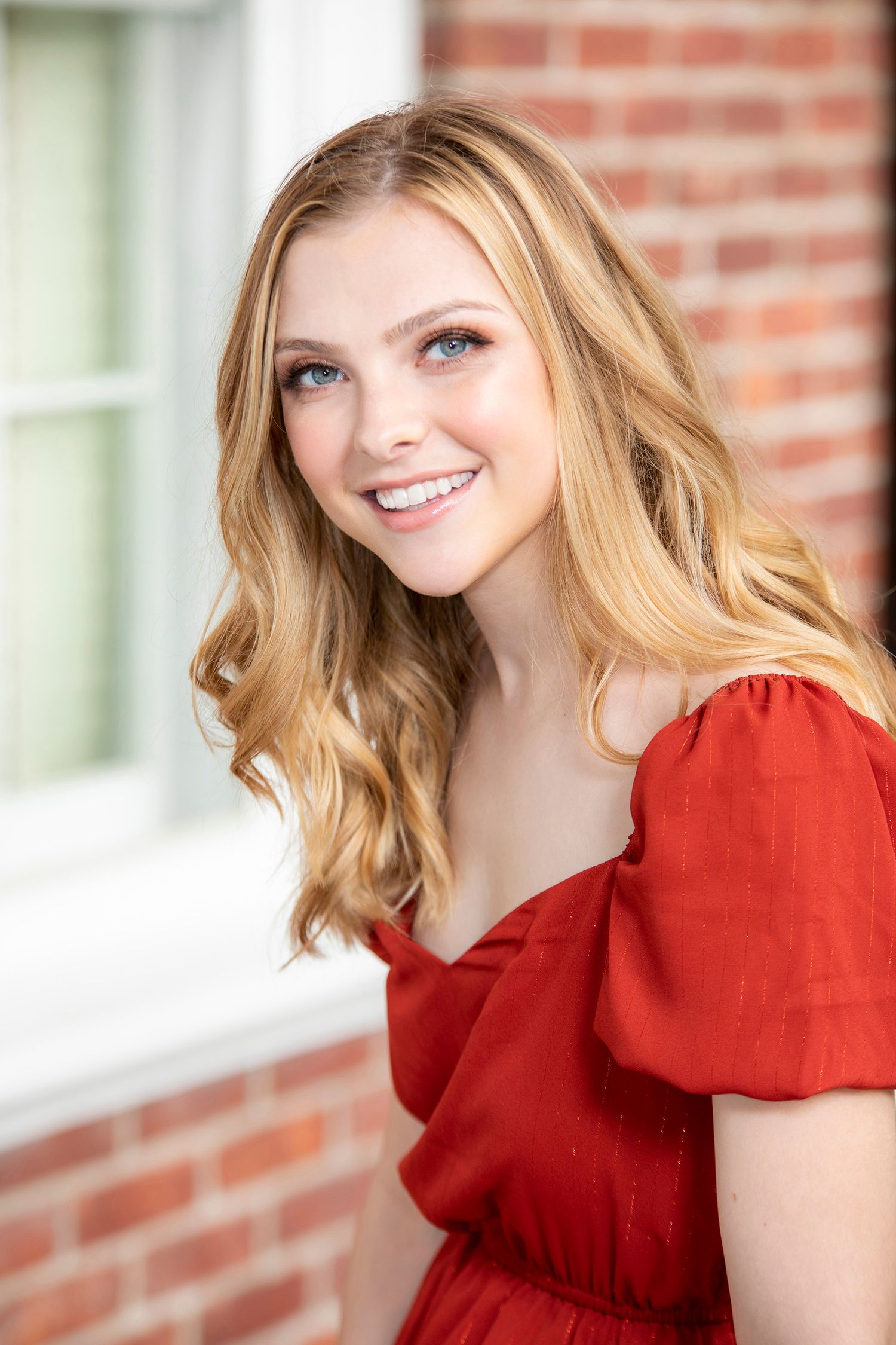 A person in a bright red top poses against a brick wall background in a series of connected portrait shots.