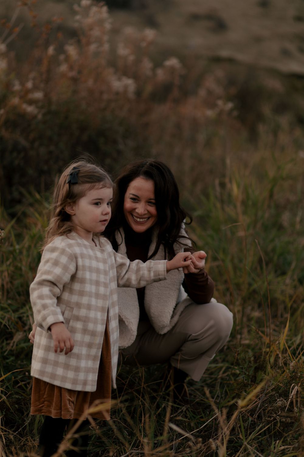 A heartwarming moment between parent and child sharing smiles in tall grass during golden hour.