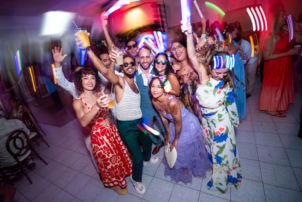 Energetic party crowd dancing and celebrating at a vibrant nightclub with colorful lighting and festive atmosphere.