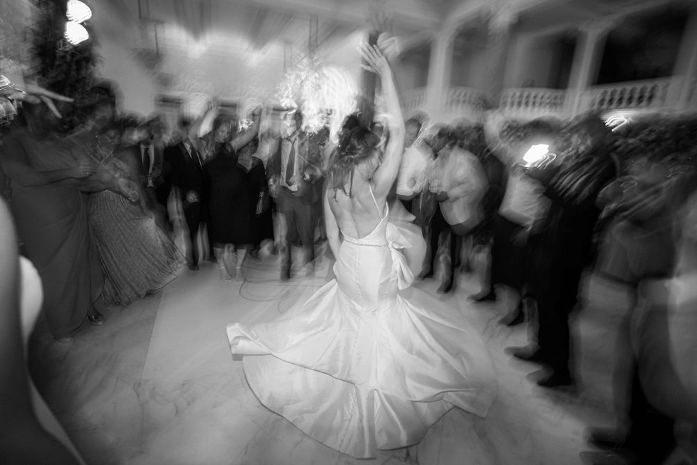 Artistic black and white photo captures spinning motion on wedding dance floor.