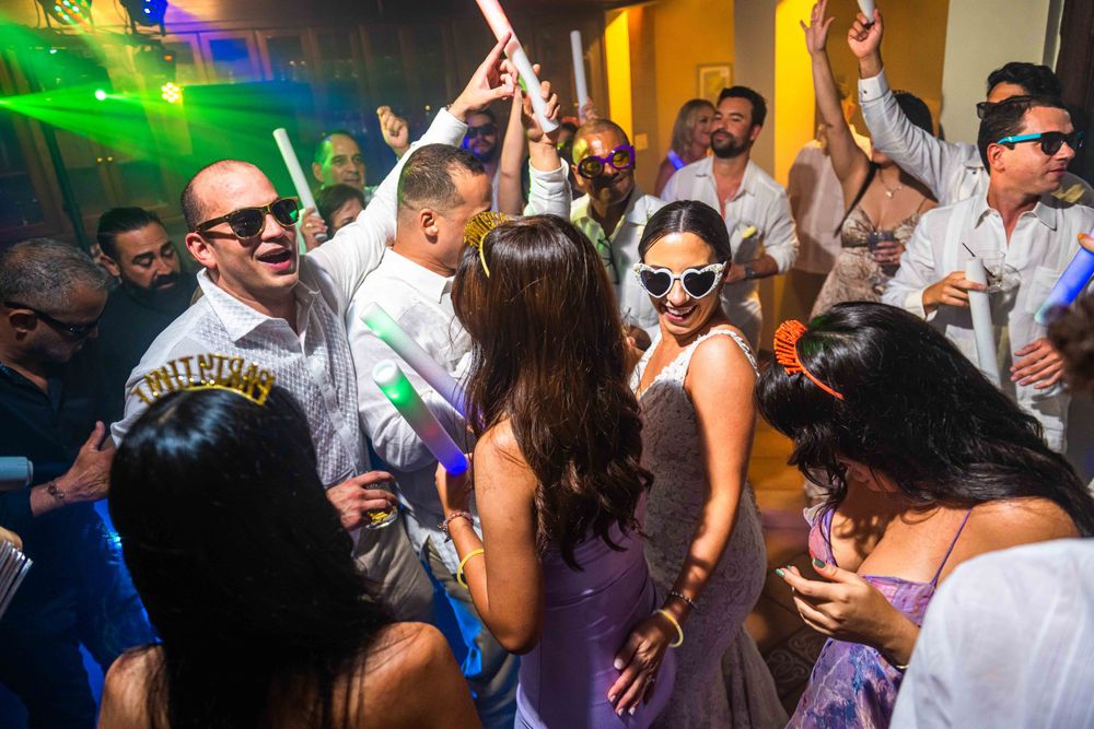 Energetic dance floor scene with wedding guests celebrating under colorful lights.