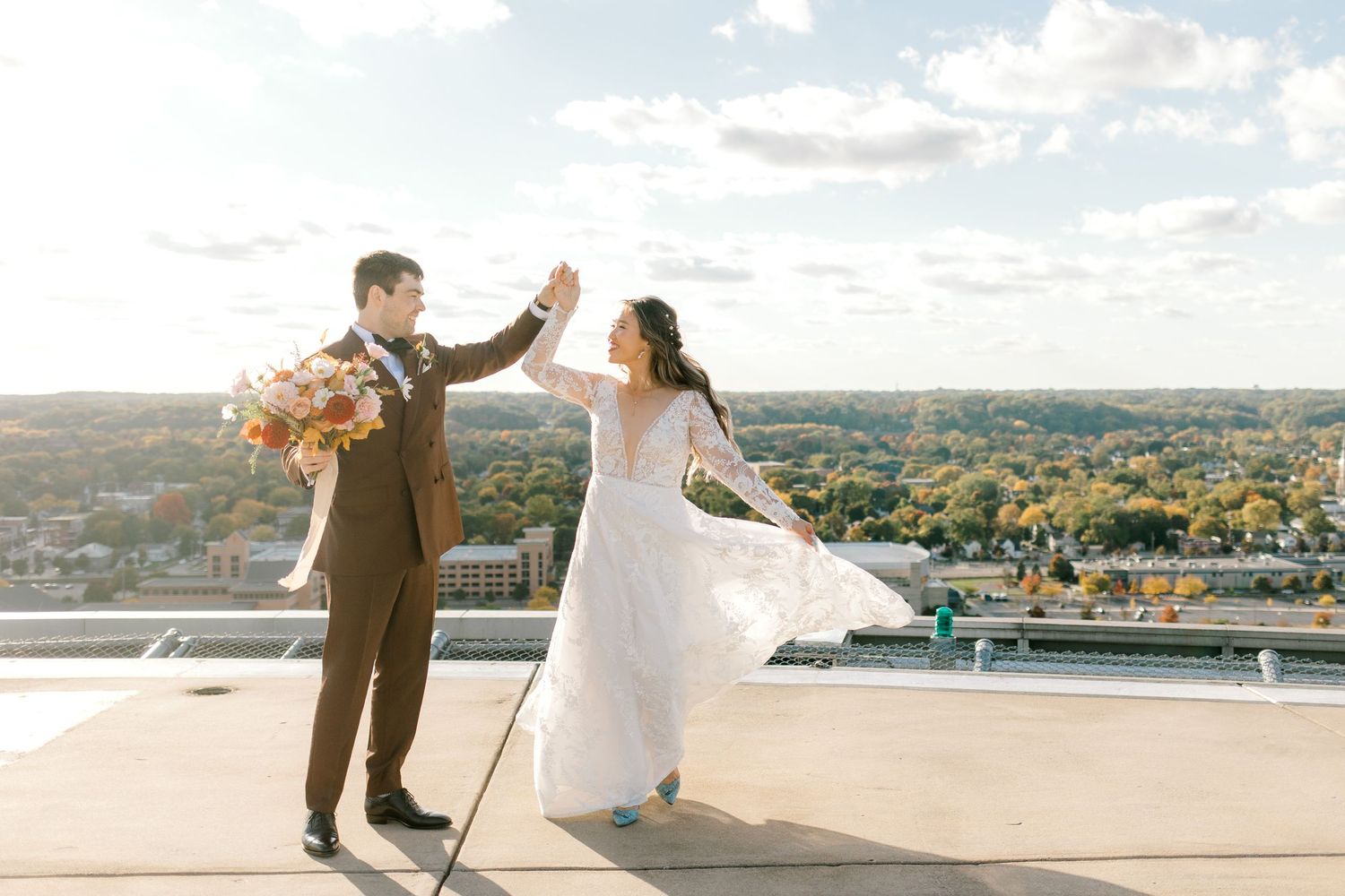 Joyful couple dancing on a rooftop with autumn cityscape in the background.