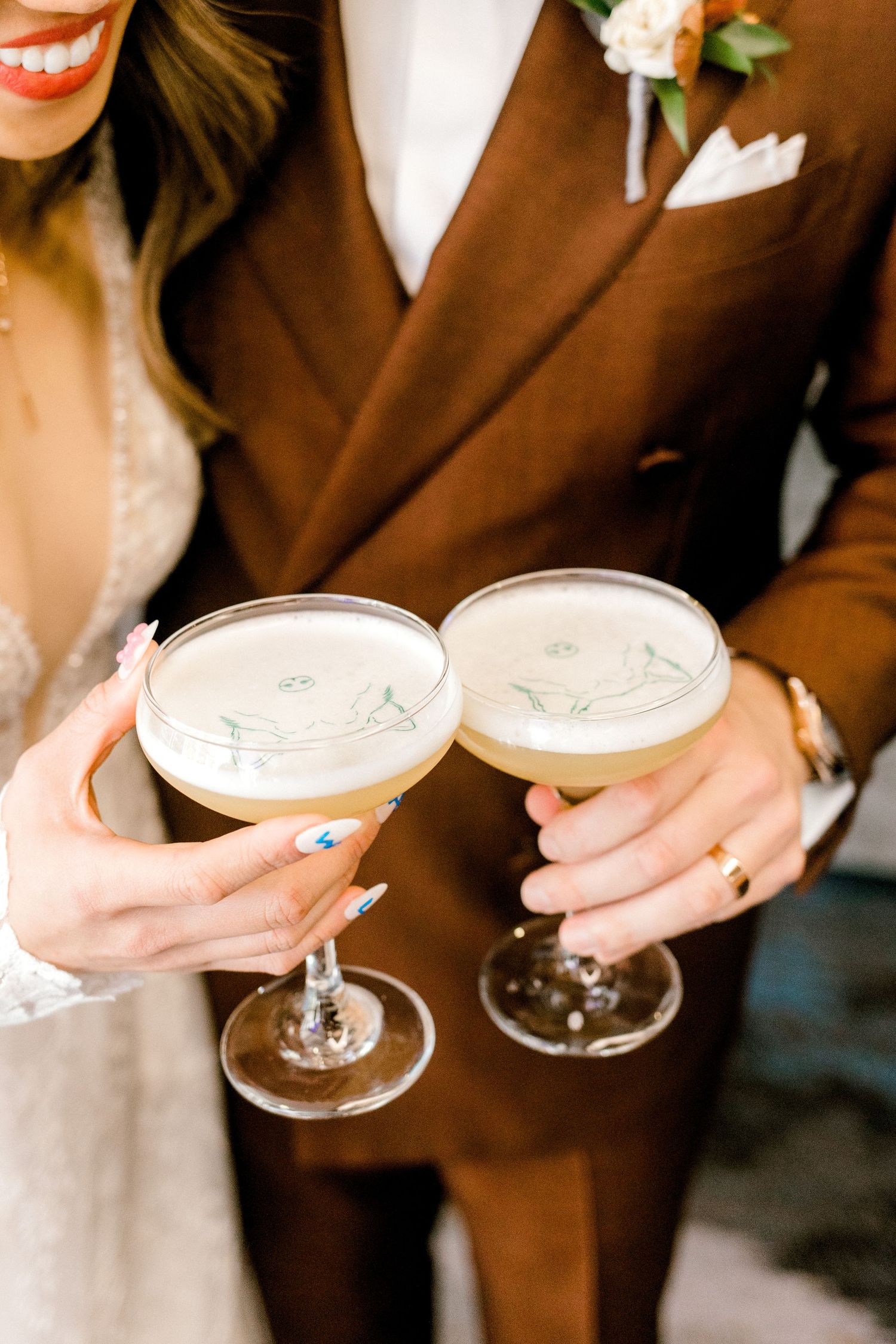 Two champagne cocktails held by hands in formal wedding attire.