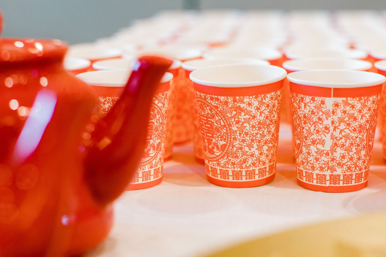 Red teapot beside matching patterned orange cups in a row.