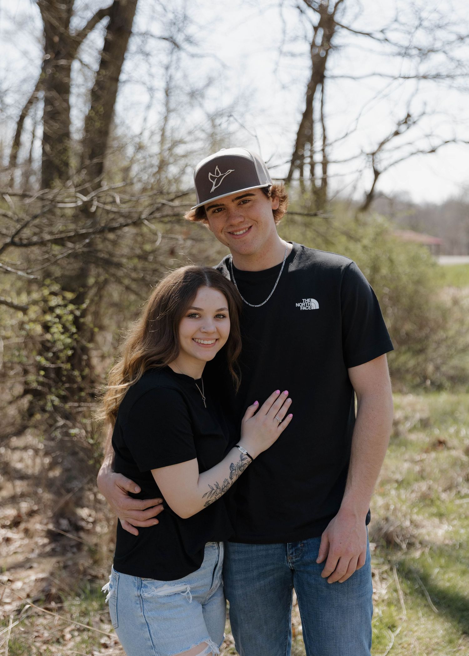 A romantic couple embraces on a wooded trail during an intimate outdoor photoshoot.