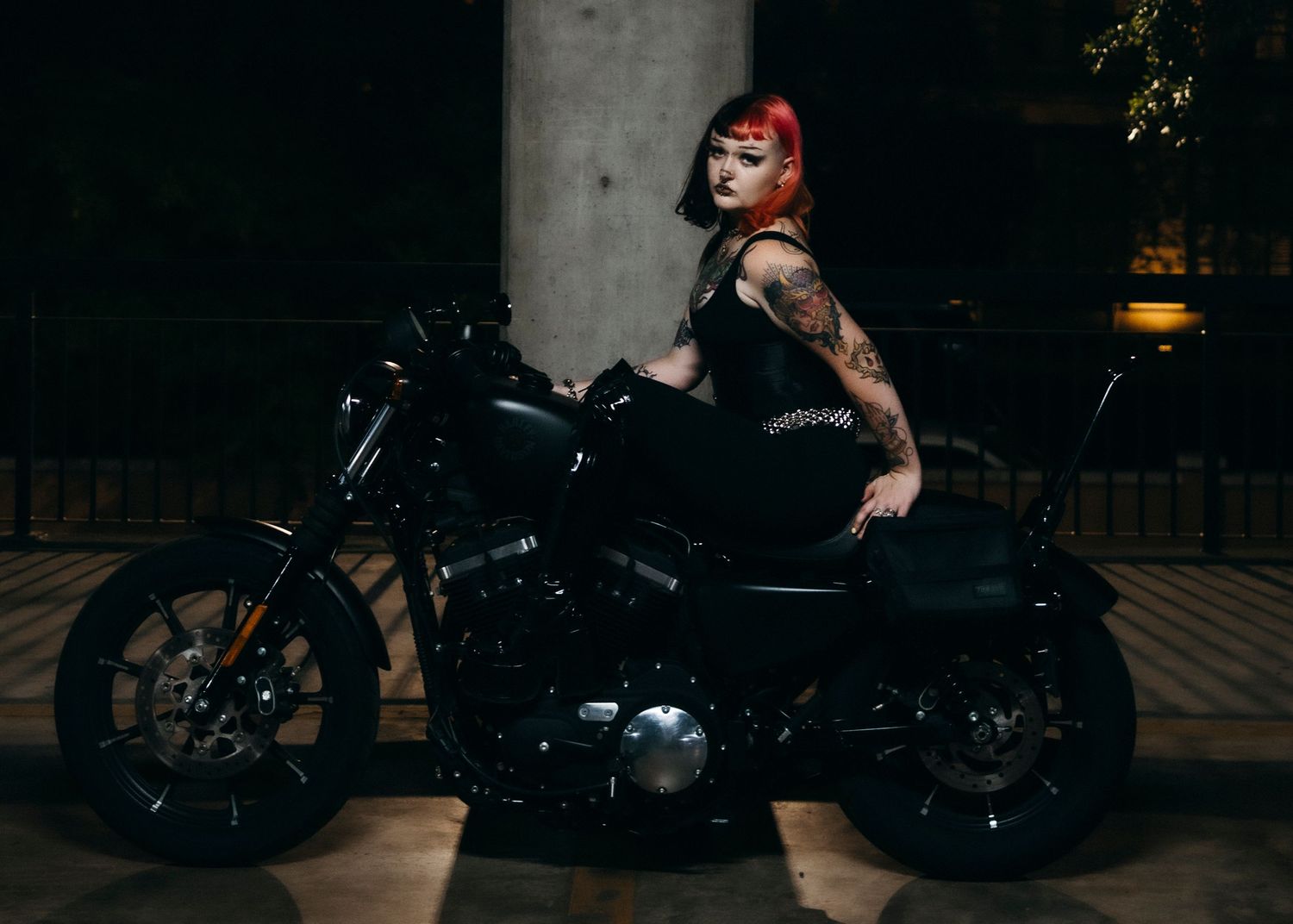 Model posing on motorcycle at night in dimly lit garage