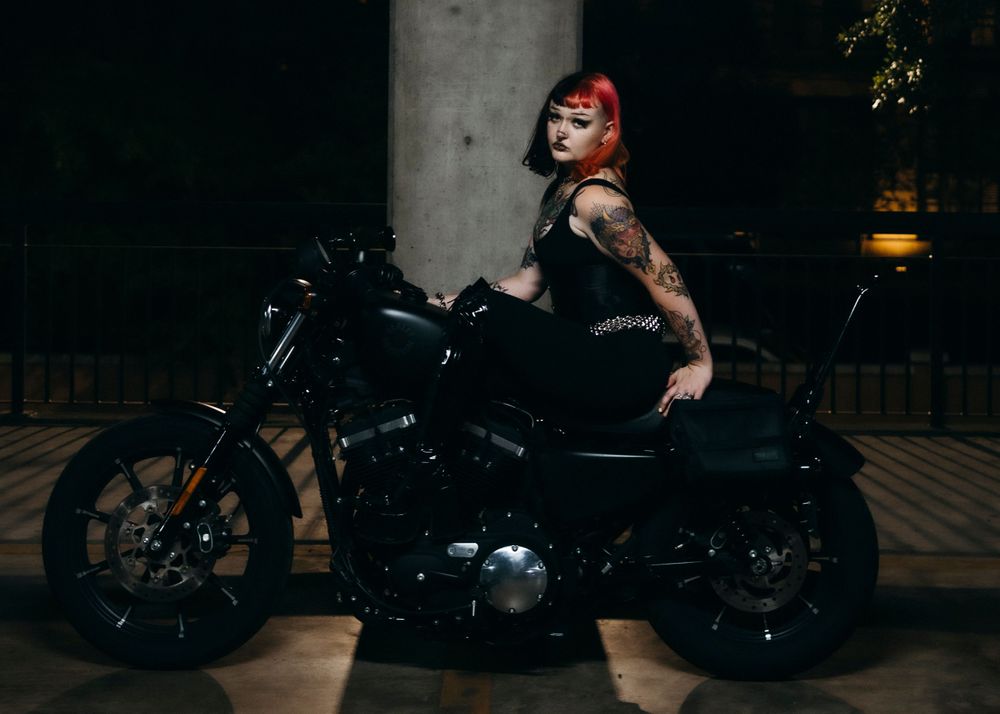 Model posing on motorcycle at night in dimly lit garage