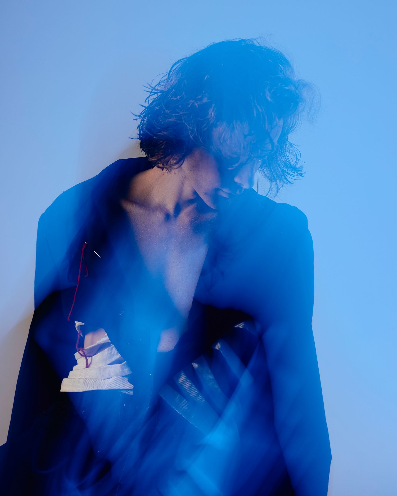 Model wearing open suit jacket, looking to the side, photo with motion blur and blue light
