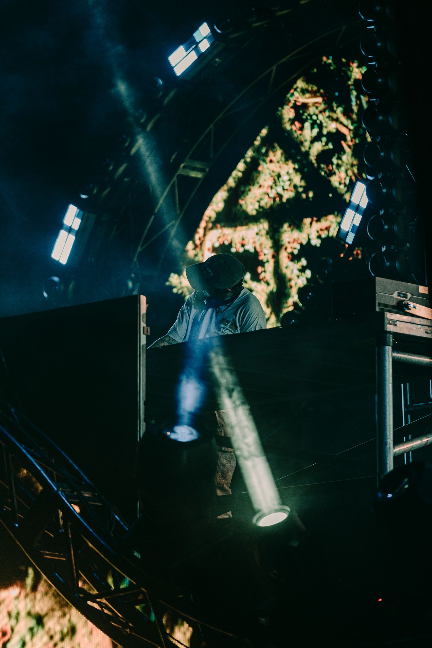 Music artist Of The Trees playing a DJ set on stage with his logo/visuals behind him and light