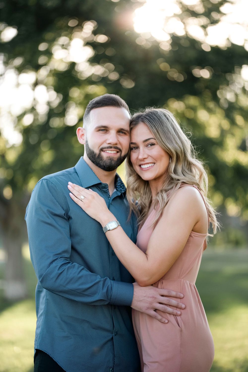 A romantic couple poses together outdoors in coordinating blue and pink outfits.