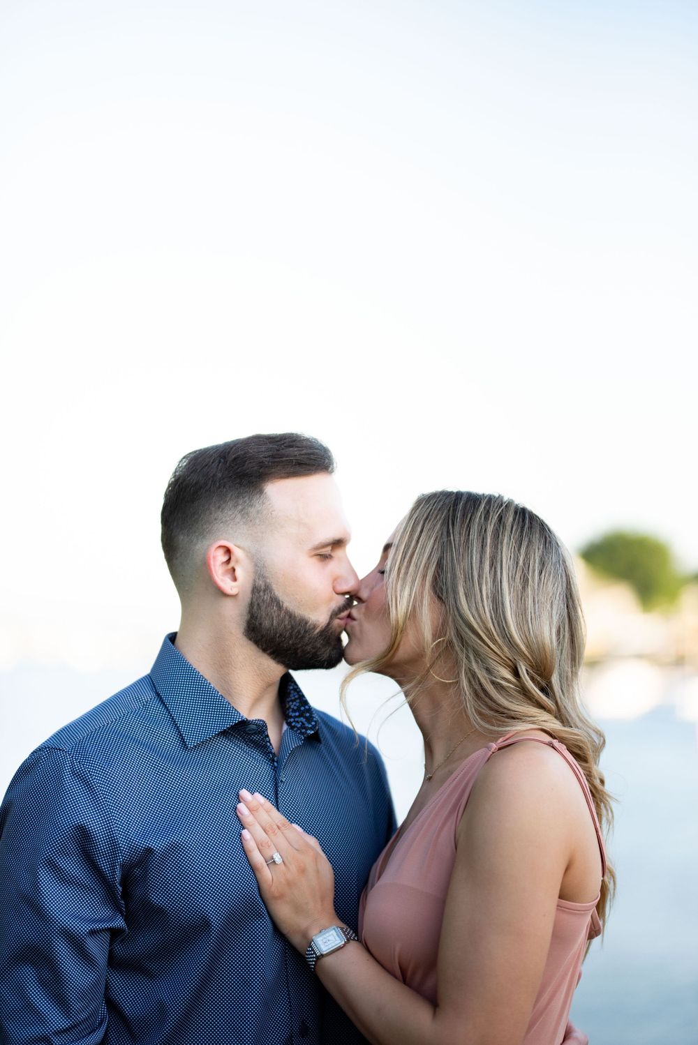 A couple sharing a tender moment by the water during sunset.