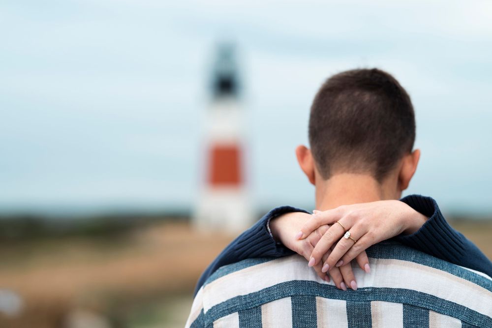 A series of people sitting together at a coastal lighthouse location wearing blue and white striped shirts.