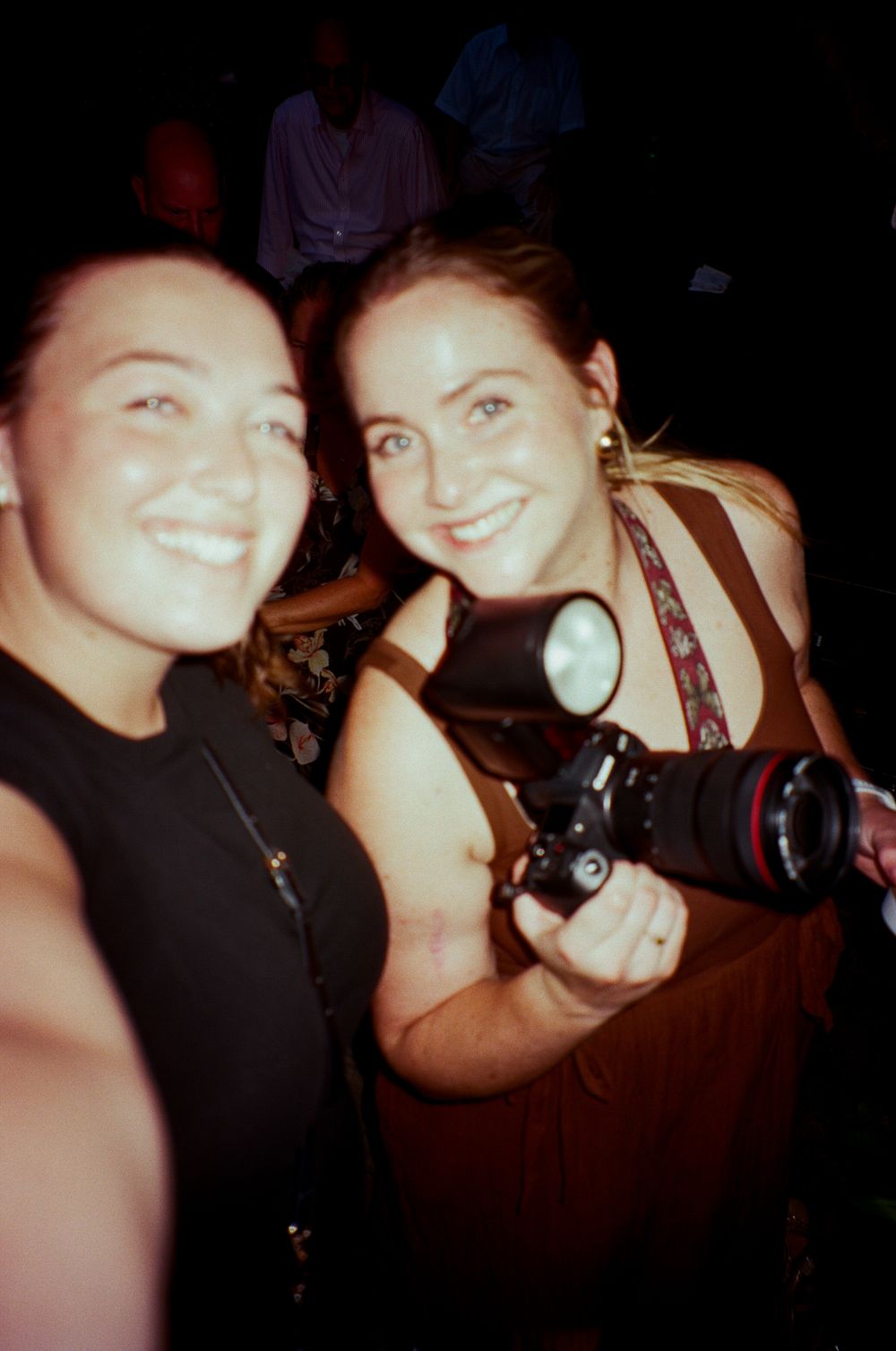 Two friends take a series of fun selfies together in dim lighting at what appears to be a social gathering.