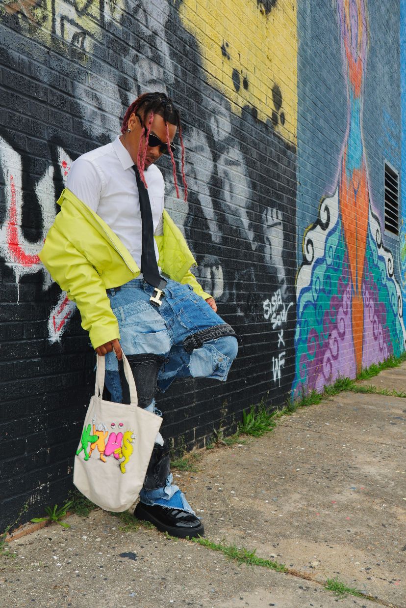 Urban fashion pose against colorful graffiti wall wearing bright yellow jacket and denim.