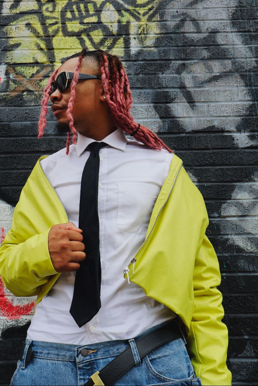 Street fashion look featuring neon yellow jacket, white shirt, black tie against graffiti wall.