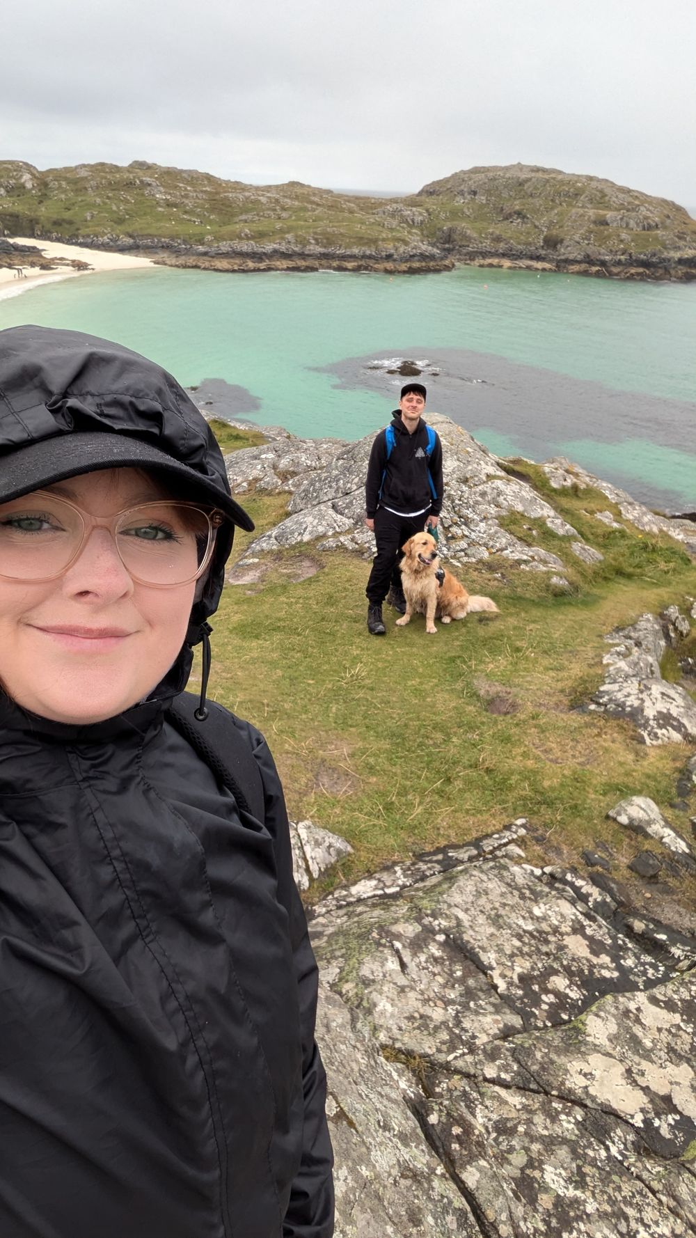 Scenic coastal view with turquoise waters and rocky cliffs along a grassy hiking trail in Scotland.