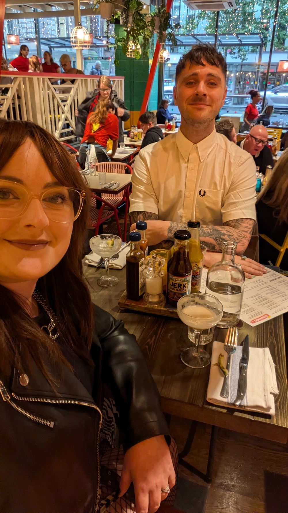 Two people dining at a restaurant table with cocktails and place settings in a cosy indoor atmosphere.