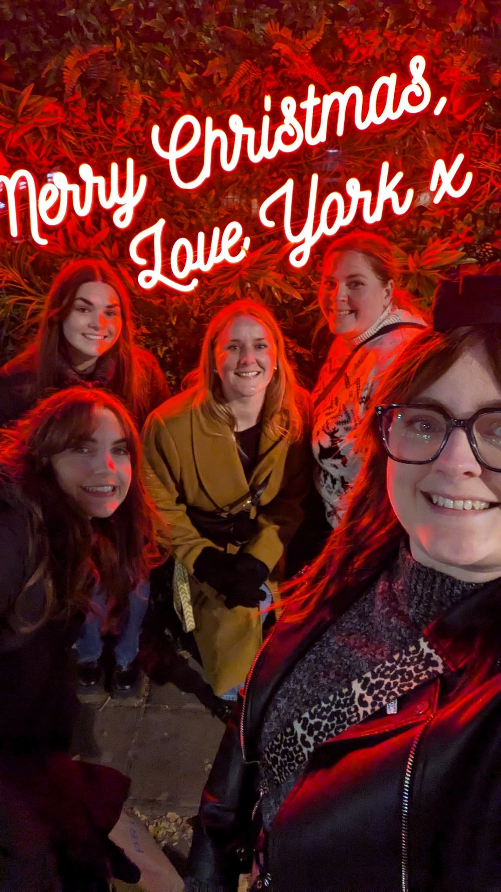 A festive holiday group photo with red lighting and text saying 'Merry Christmas, Love York x'.