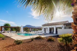 Luxury white modern home with palm trees and mountain views, outdoor poolside in Palm Springs real estate listing.