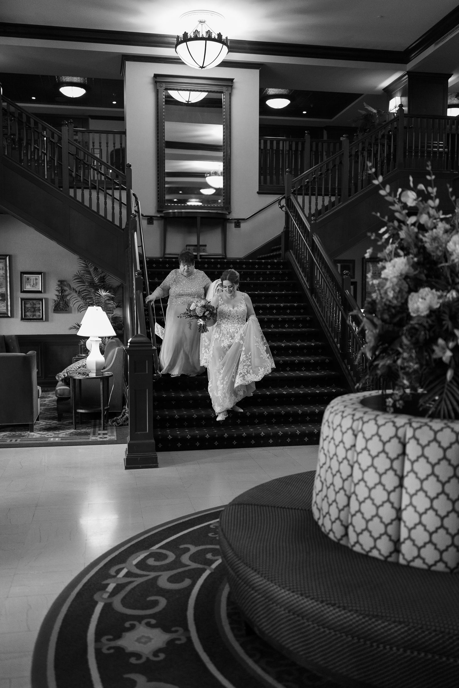 Elegant black and white photo of grand hotel staircase with ornate railings, chandeliers and detailed interior decor.