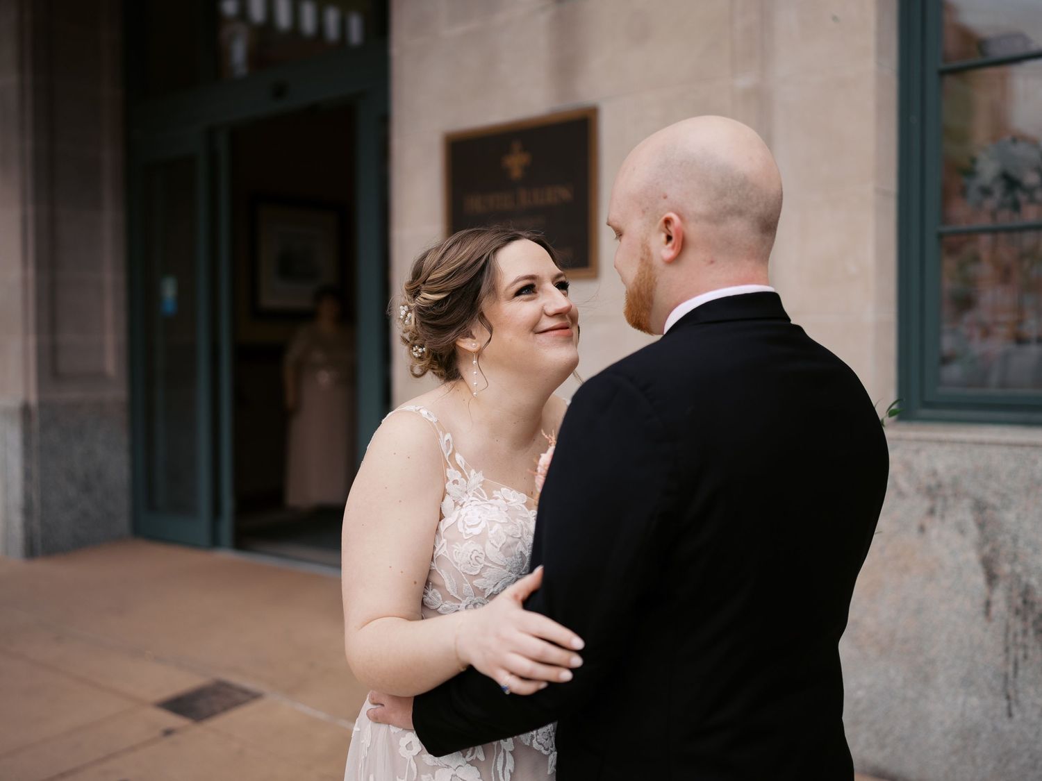 A newly married couple share a joyful moment together on their wedding day outside a building.