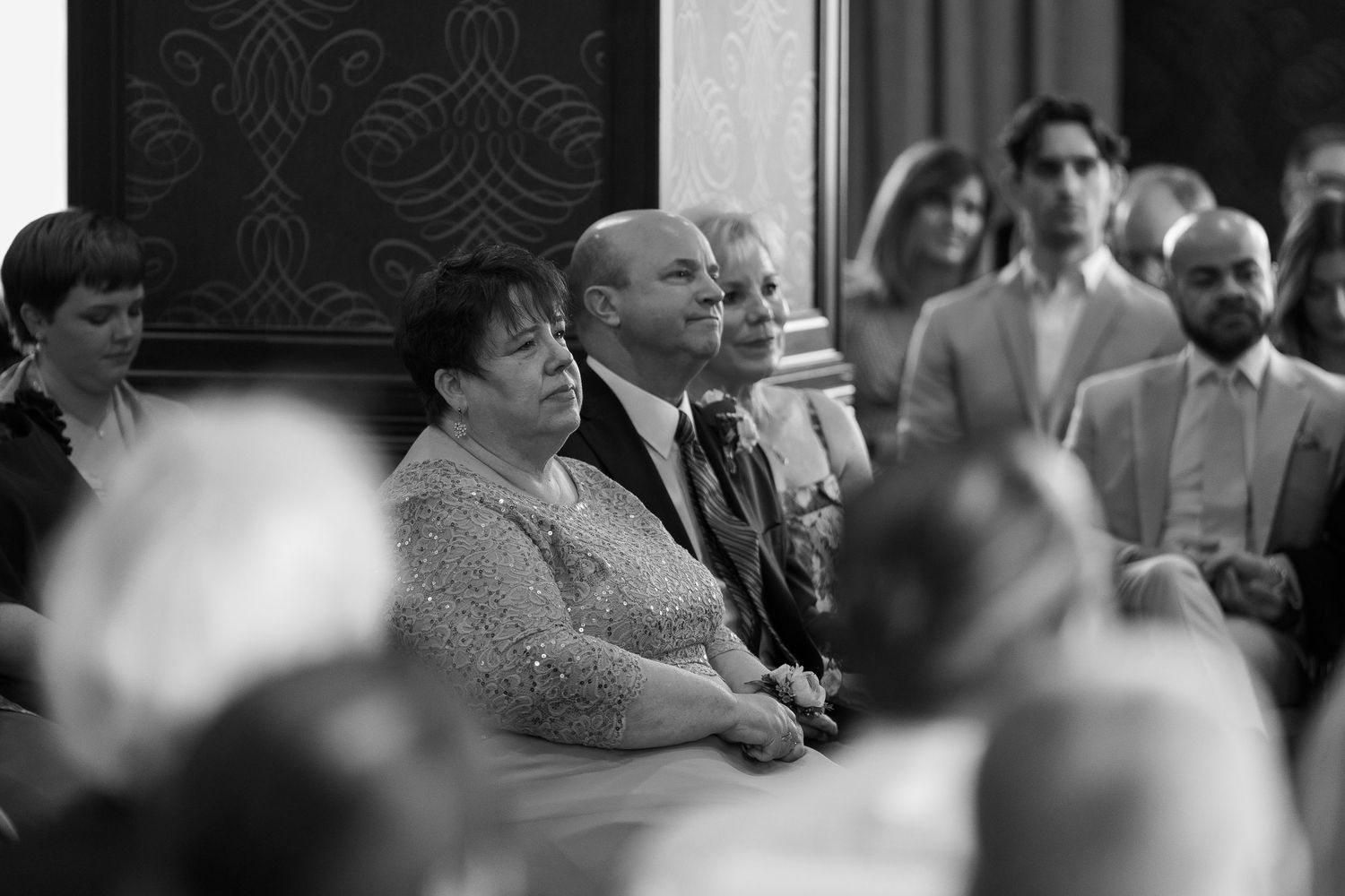 Black and white photo of guests sitting in church pews during a wedding ceremony.
