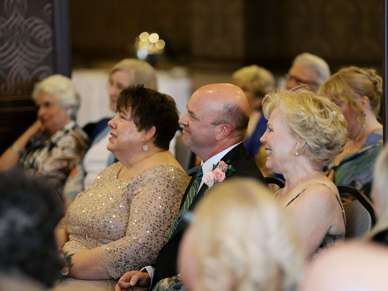 Wedding guests seated in formal attire watching the ceremony with joyful expressions.