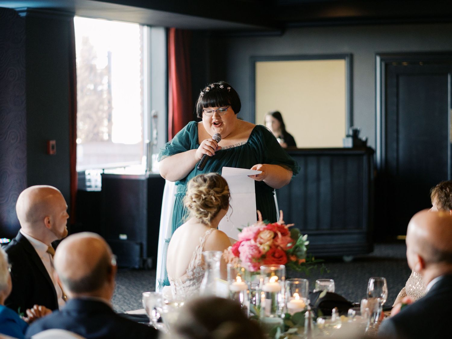 A speaker gives an emotional speech at a formal reception with guests seated at decorated dining tables.