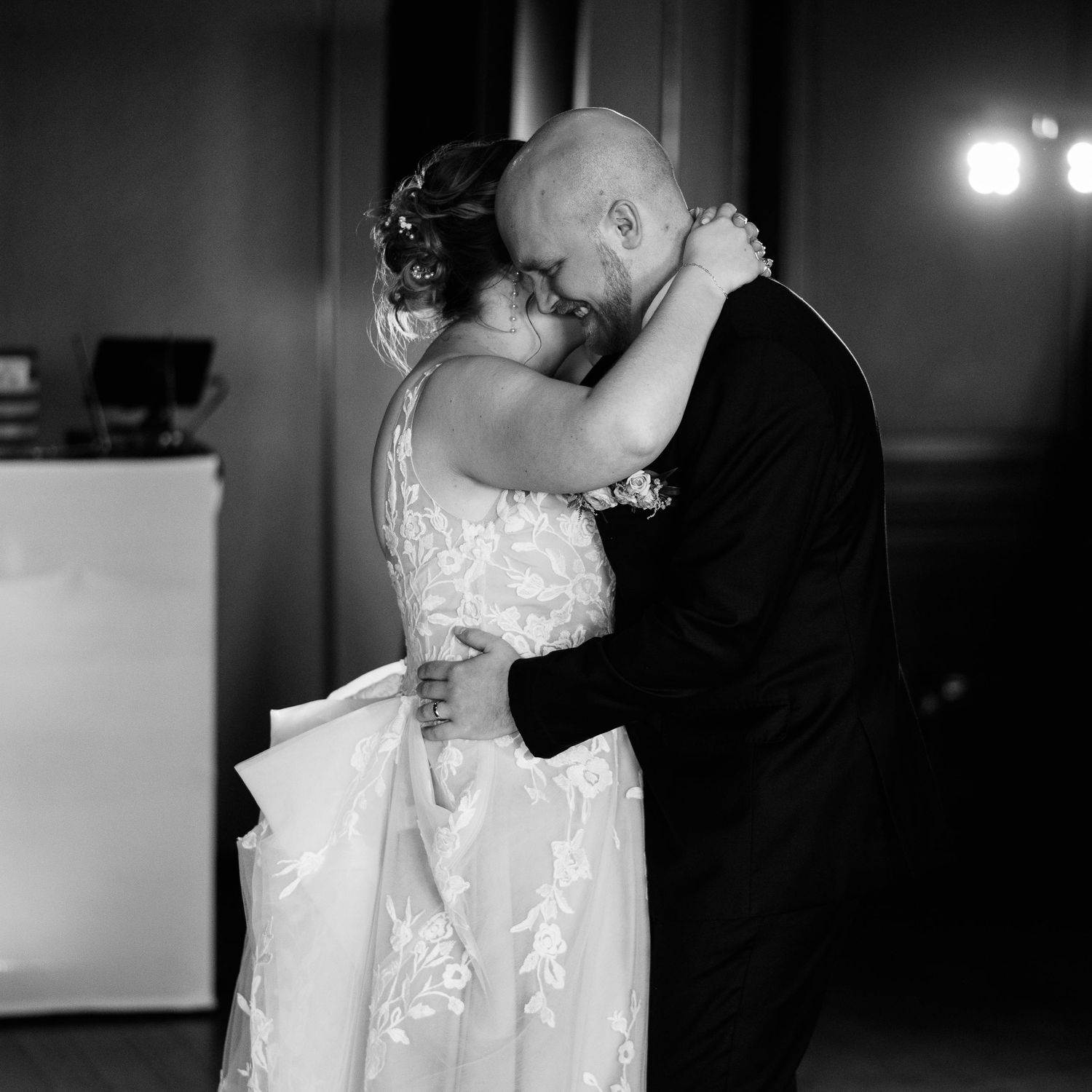 A couple shares their first dance as newlyweds in an intimate black and white wedding reception moment.