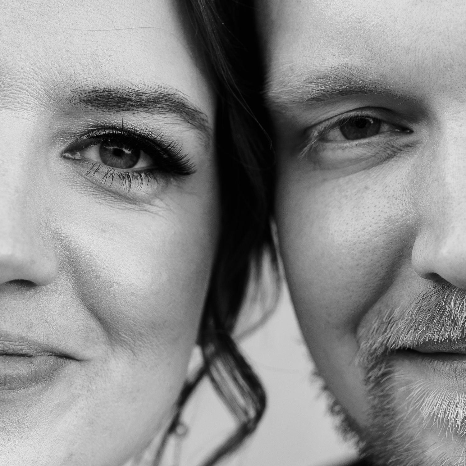 Black and white close up portrait of two faces, with one smiling and the other showing a gentle beard.
