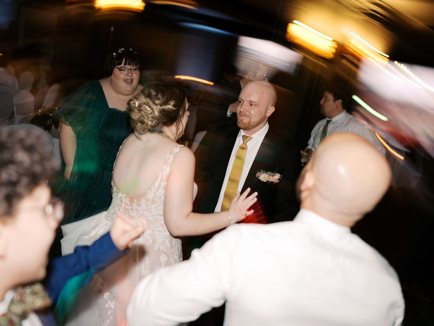 People dancing and socializing at what appears to be a wedding reception with motion blur effects and warm lighting.