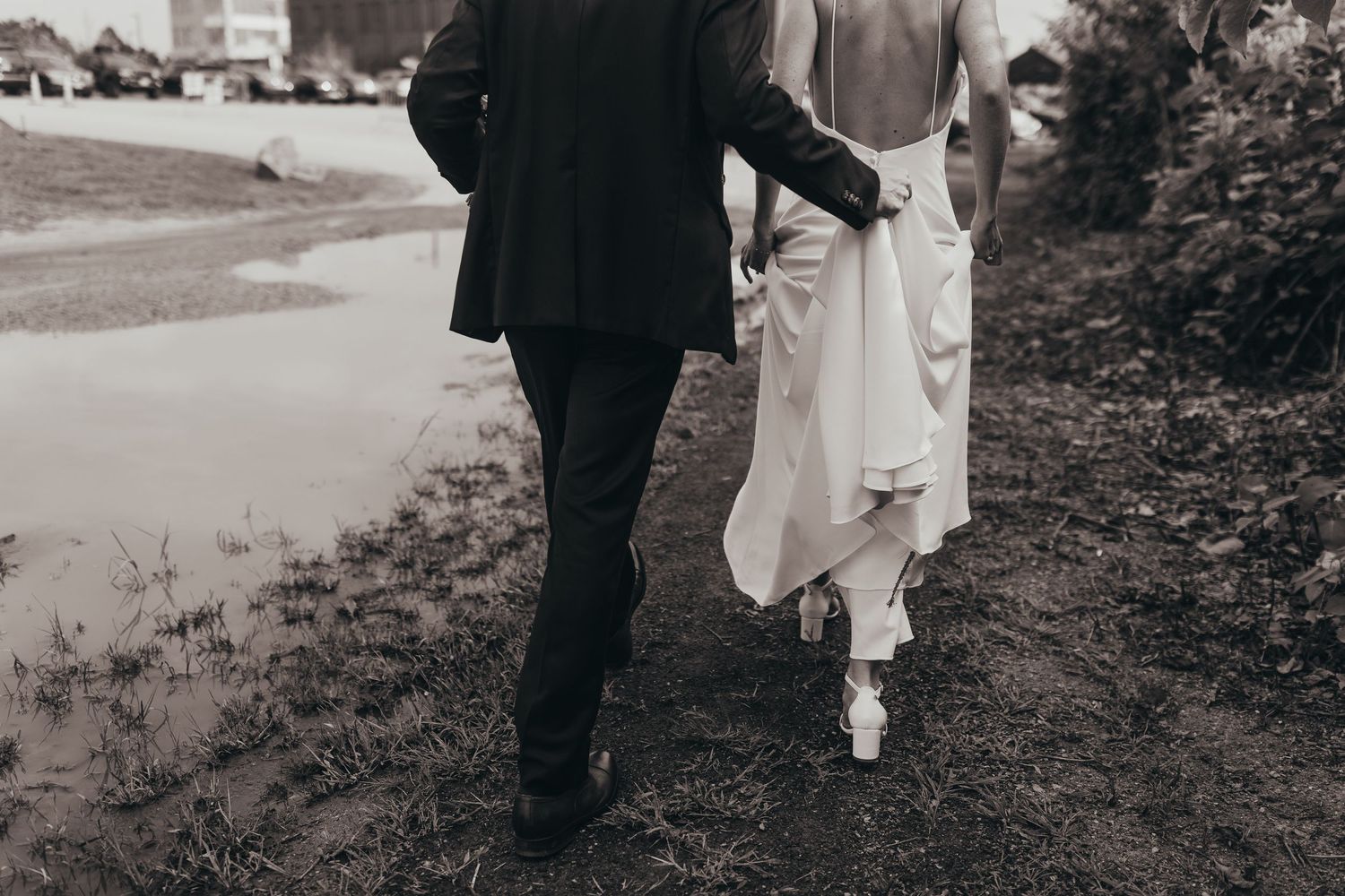 A black and white wedding photography sequence showing a couple walking along a hillside path.