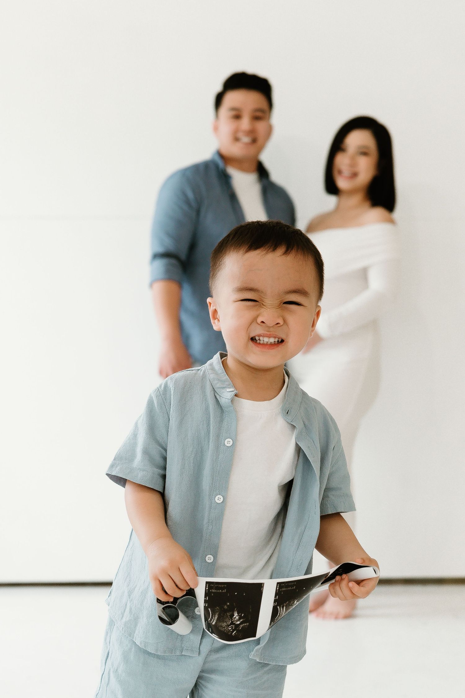 Family in coordinated blue and white outfits poses in bright studio setting.