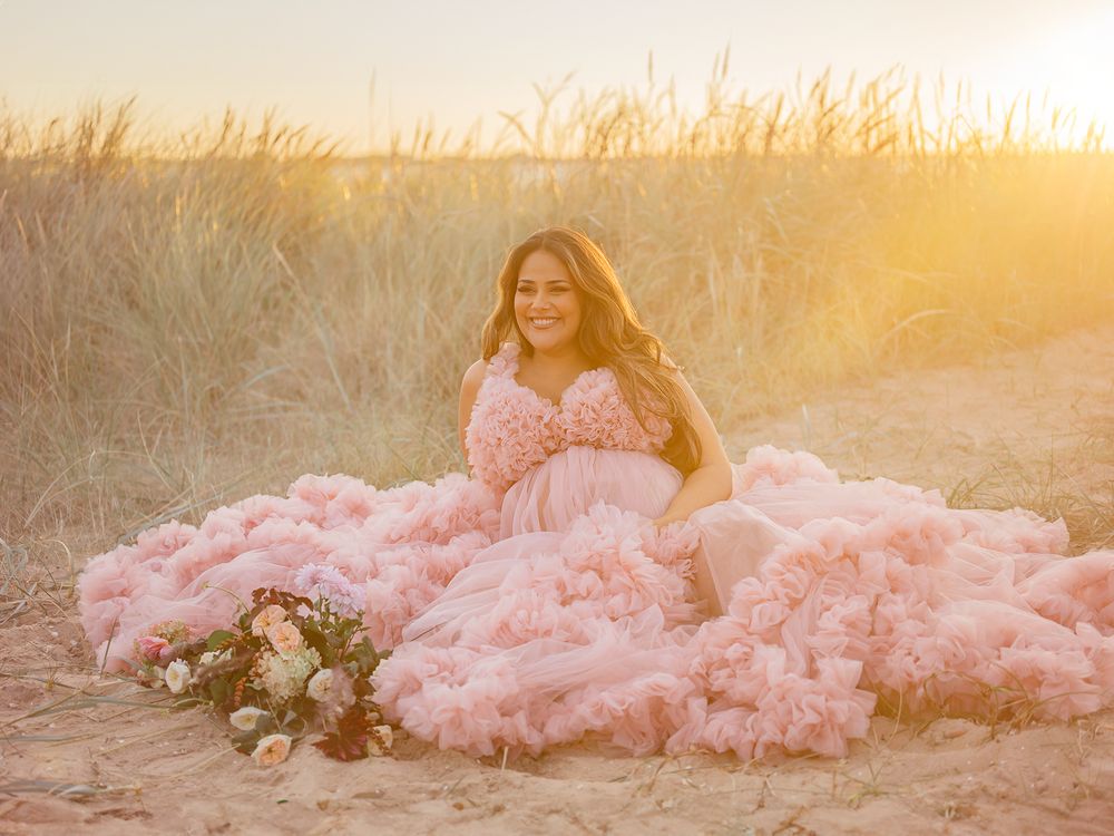Gravid mamma sitter på sandstrand i motljus, Gravidfotografering i Västerås, goldehour, MemoriesbyM, pastell