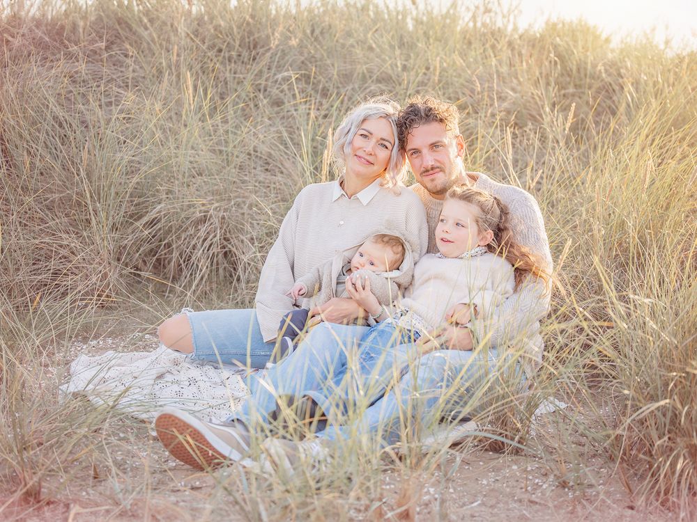 Barnfamilj sitter på sandstrand i motljus, Familjefotografering i västerås, Barnfotografering i Västerås, goldenhour, pastell, MemoriesbyM