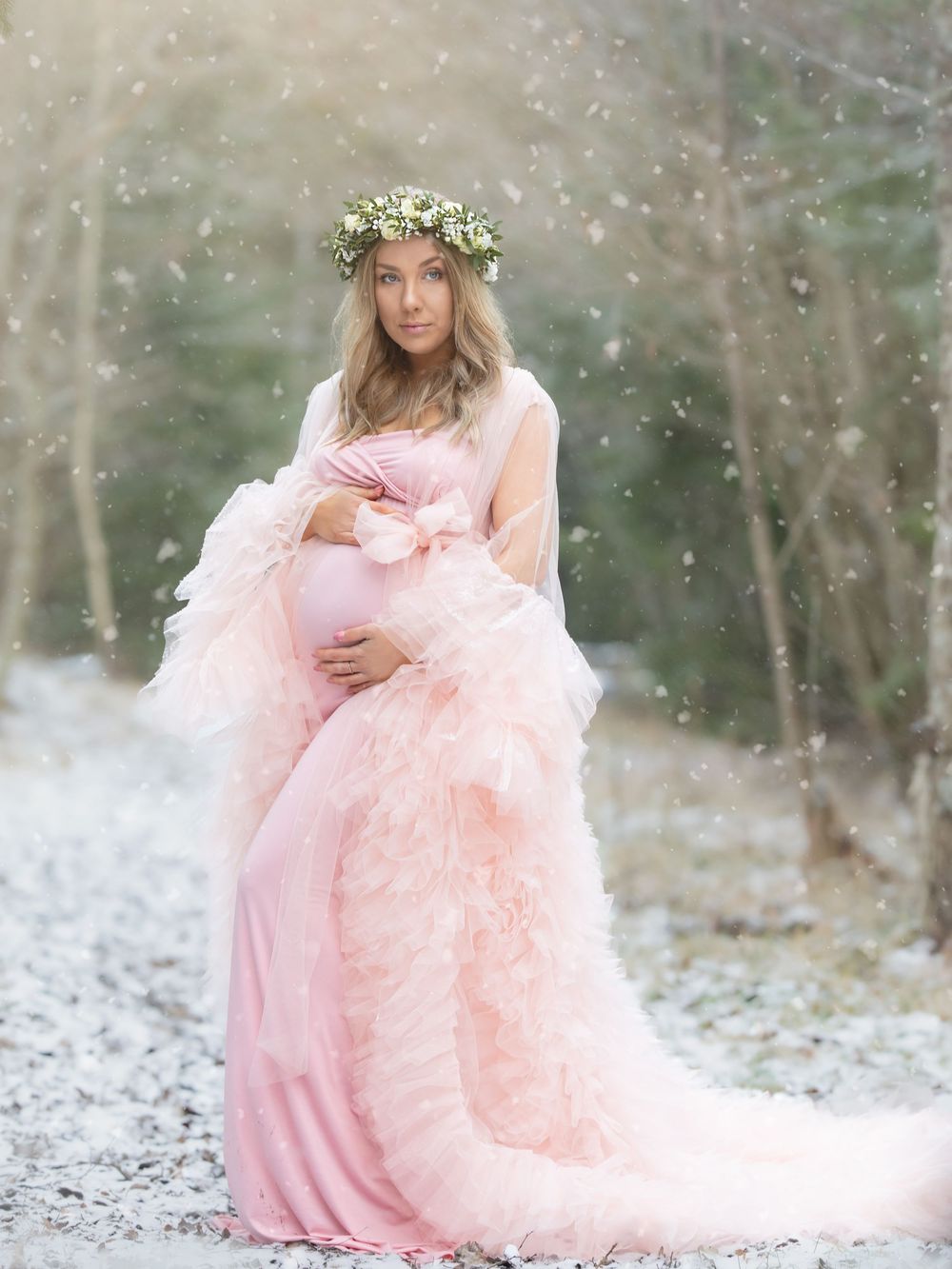 Gravid kvinna i rosa klänning står i snölandskap, Gravidfotografering Västerås, MemoriesbyM