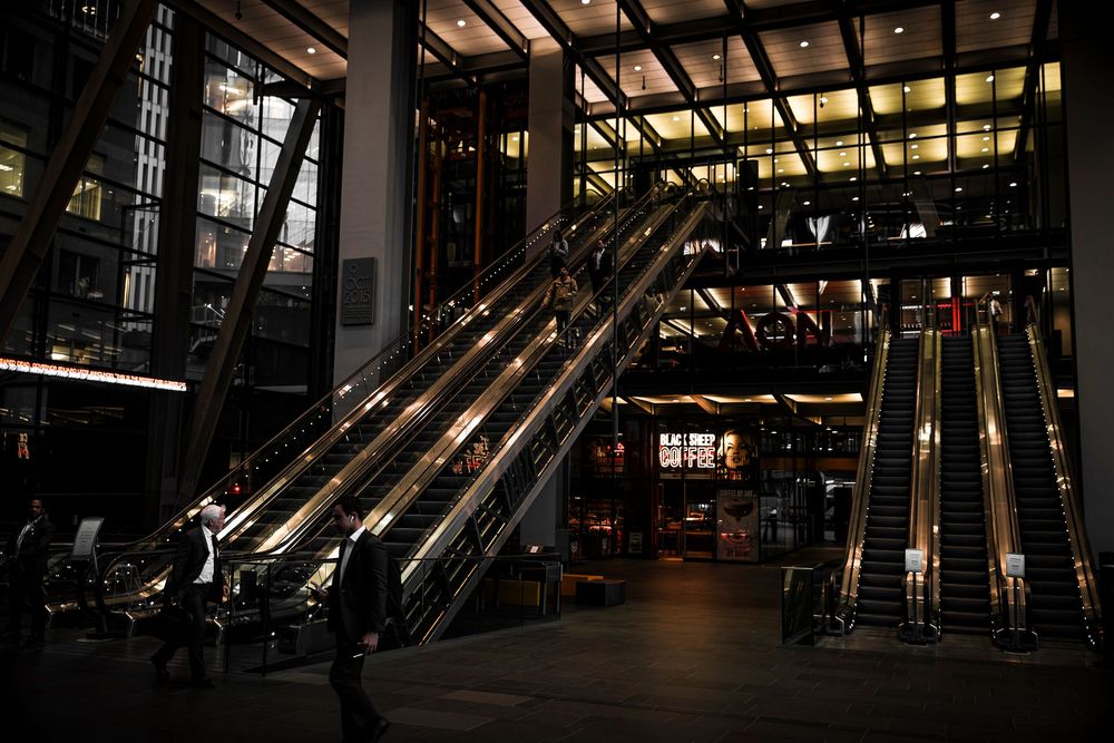 Panoramic view of modern transit station with illuminated escalators and architectural glass details at dusk.