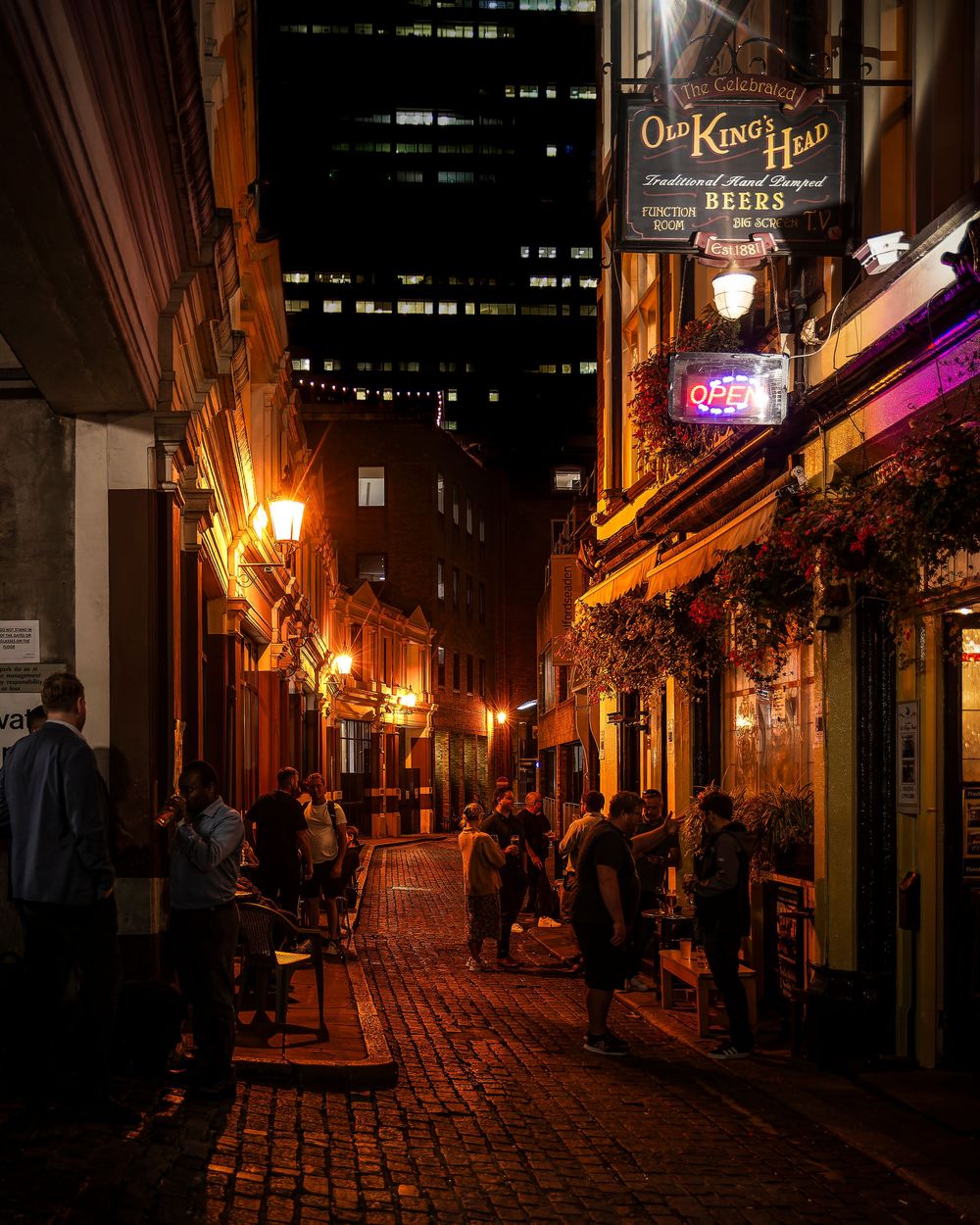 Nighttime view of illuminated cobblestone streets and historic buildings in a charming European neighborhood.